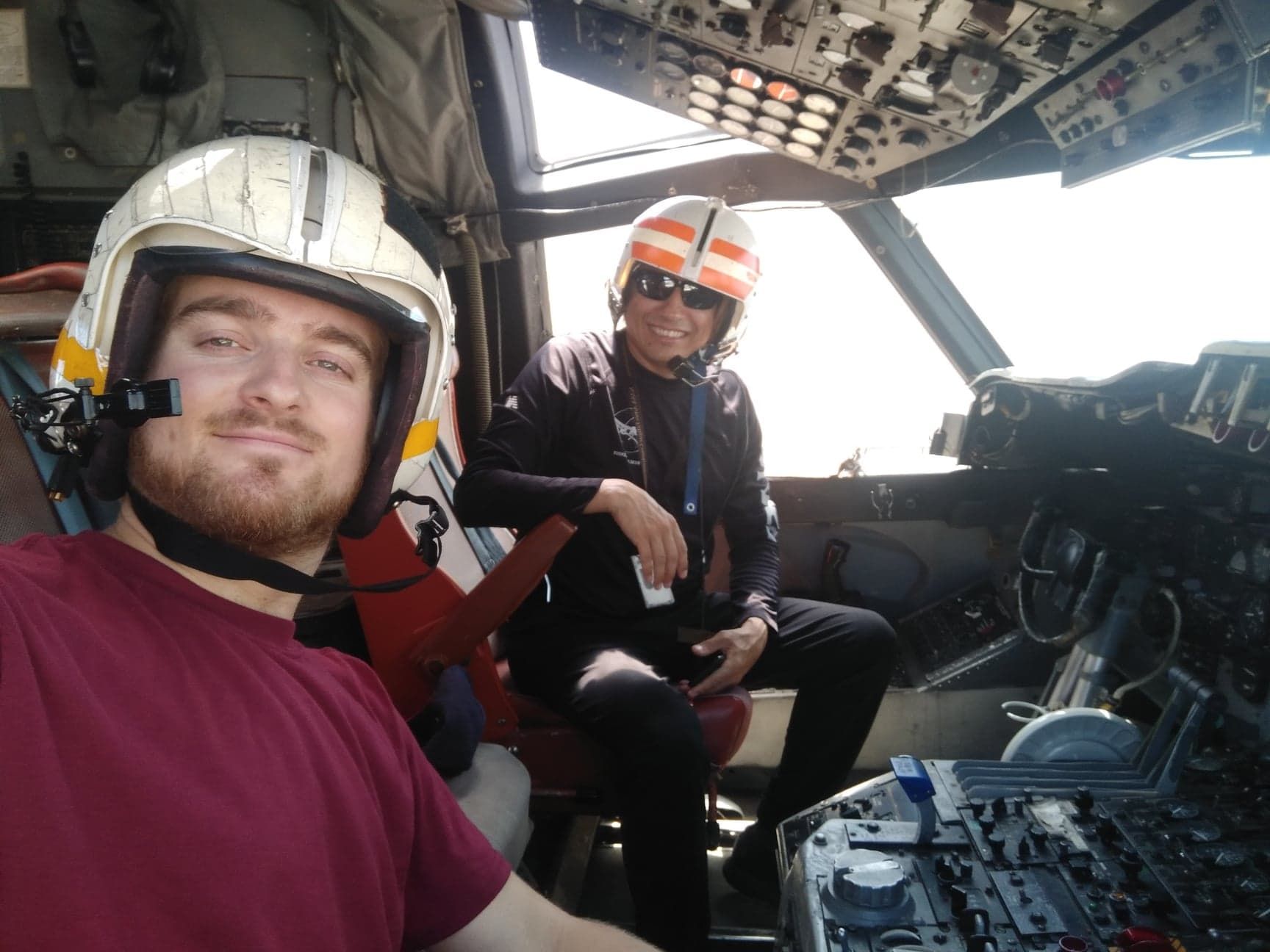 Sam Naef and a colleague wearing helmets in an old aircraft cockpit